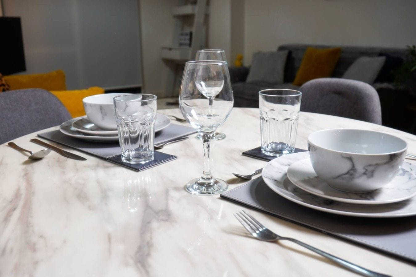 Une table à manger dressée avec des assiettes, des bols, des verres et des couverts.