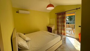 A bedroom with a bed, a desk, a chair, a window with curtains, and a balcony.