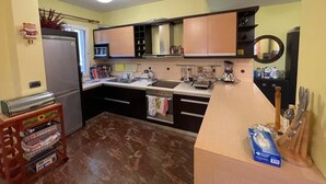 A compact kitchen with a refrigerator, stove, sink, and various appliances.
