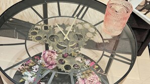 A round glass table with a black metal frame, decorated with flowers and a gear-like centerpiece. - Central London Studio for 2 with Kitchenette (London)