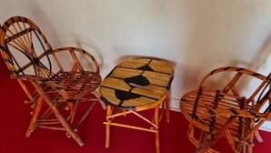 Une pièce comprenant trois chaises en osier et une petite table en bois.