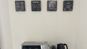 Eine Küchenzeile mit Mikrowelle, Kaffeemaschine und Stauraumschränken.