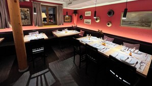 Un restaurante con mesas y cabinas dispuestas para comer, con paredes rojas y obras de arte.