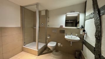 Ein modernes Badezimmer mit einer gläsernen Duschkabine, einer weißen Toilette und einem Waschbecken mit Spiegel darüber.