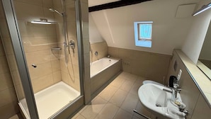 Un baño moderno con ducha envuelta en vidrio, una bañera independiente y un lavabo con espejo.