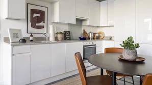 Una cucina moderna con mobili bianchi, un tavolo da pranzo con sedie e una pianta in vaso sul tavolo.