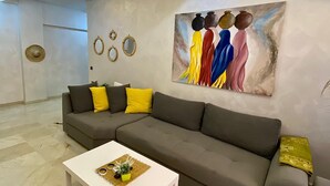 Una sala de estar moderna con un sofá seccional gris, una mesa de centro blanca y un cuadro abstracto grande en la pared.