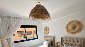 Un dormitorio con dos camas, una lámpara colgante de ratán y vistas al exterior.