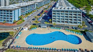 A resort with a large swimming pool, multiple hotel buildings, and a parking area.