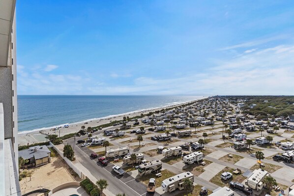 Un parque para vehículos recreativos grande, con hileras de casas rodantes y una playa al fondo.