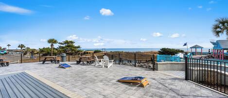 A wooden deck with outdoor seating, a view of the beach, and a gazebo.