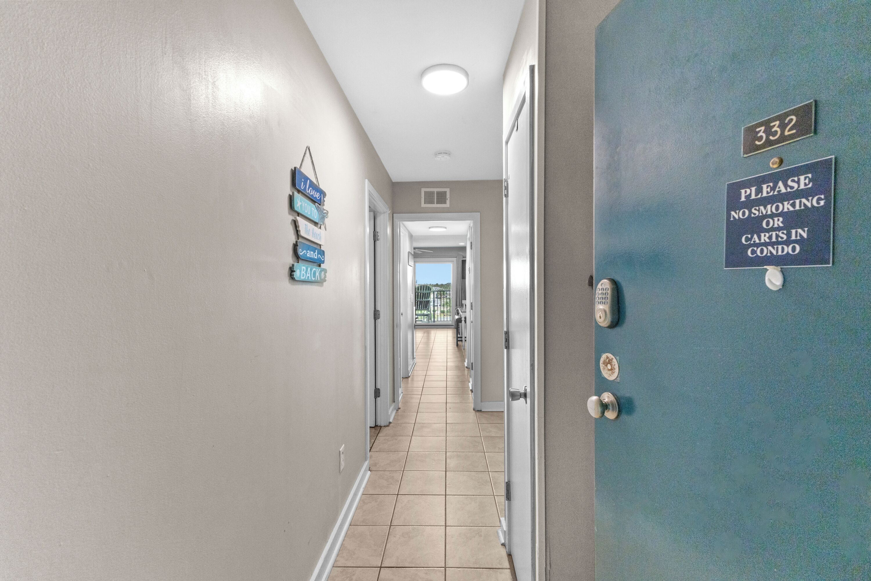 A hallway with a blue door marked "332" and a "NO SMOKING OR CARTS IN CONDO" sign.