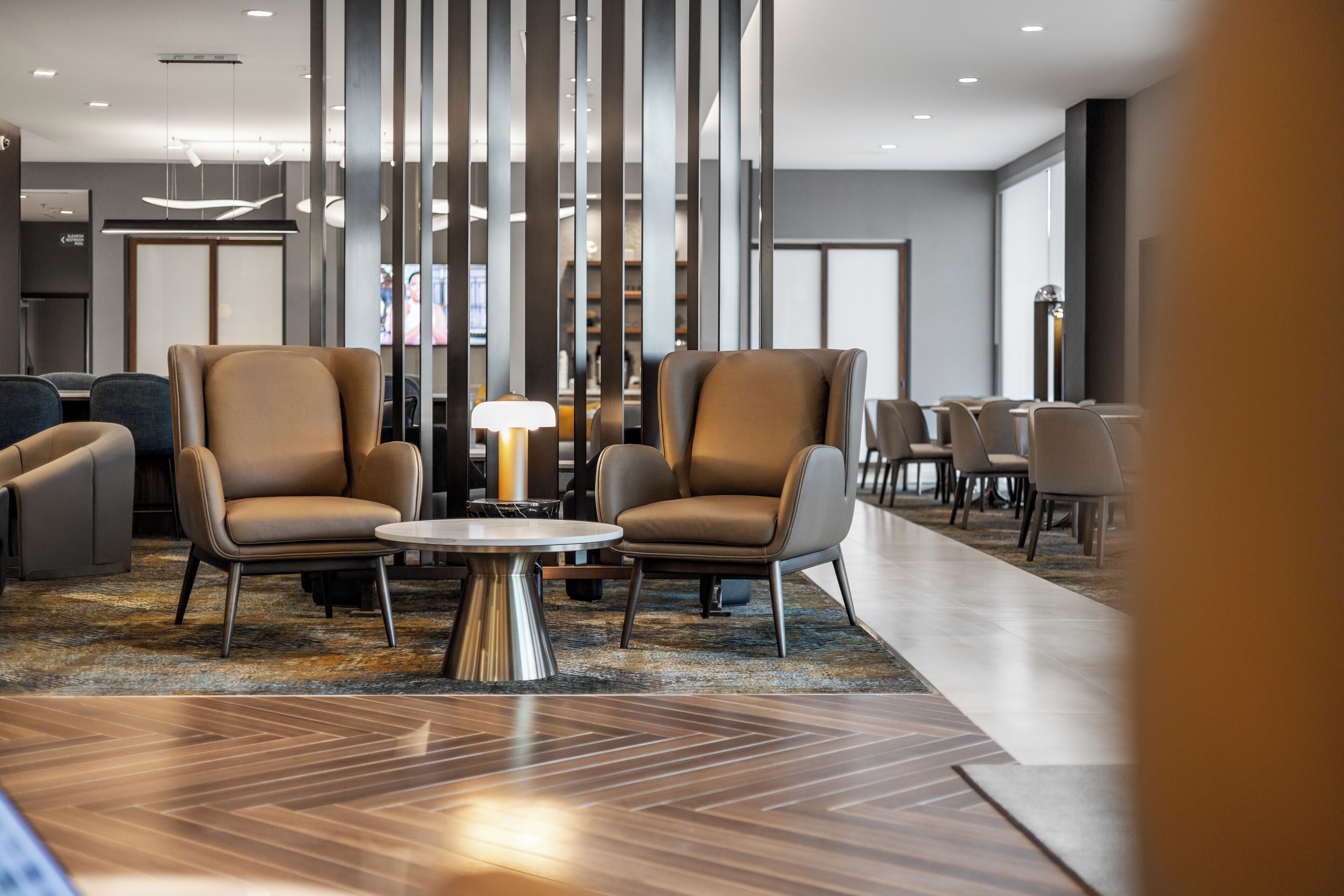 Eine moderne Lobby mit zwei Ledersesseln, einem runden Tisch und einem gemusterten Teppich.