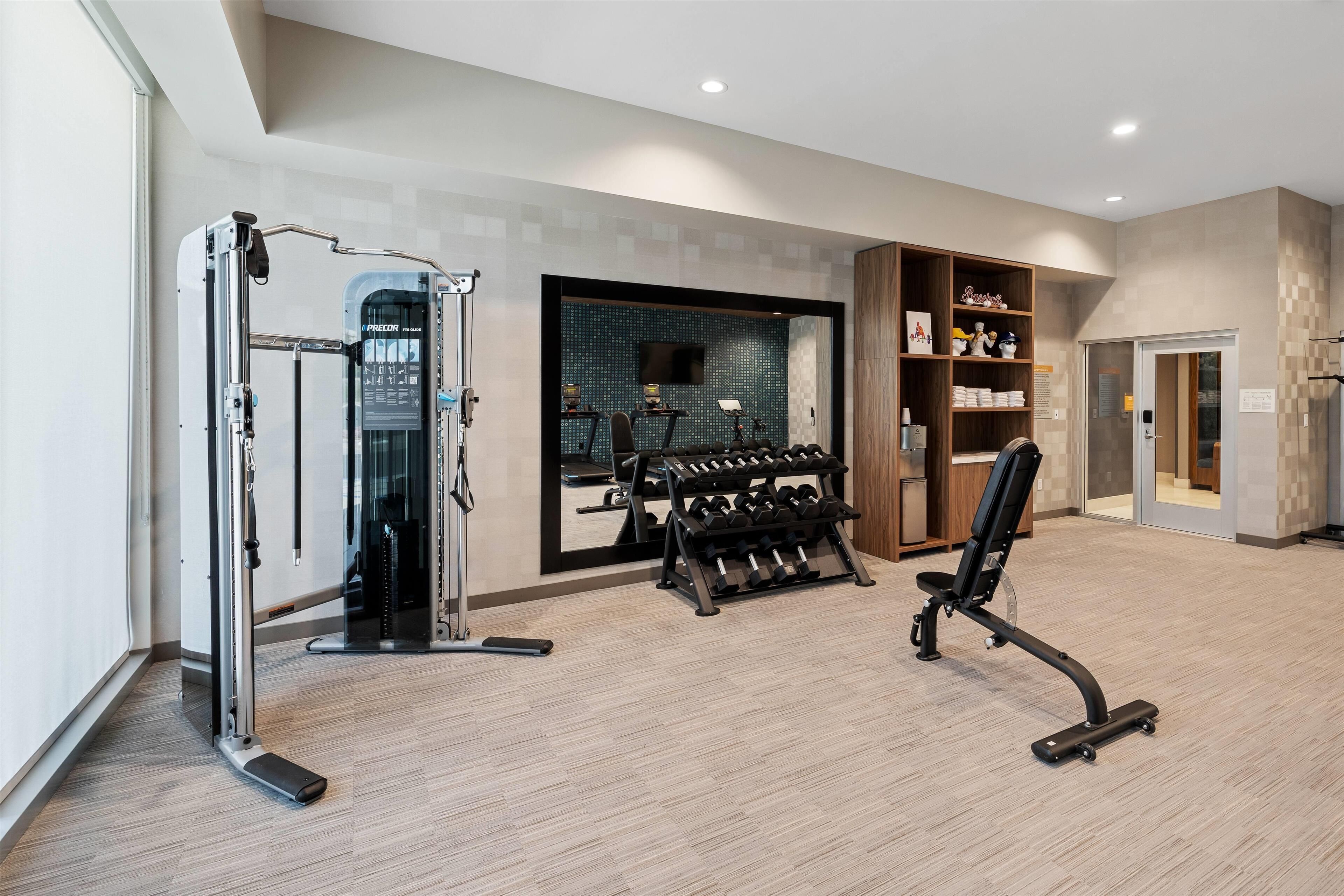 Ein modernes Fitnessstudio mit Trainingsgeräten, einem Gewichtständer und einem Spiegel.
