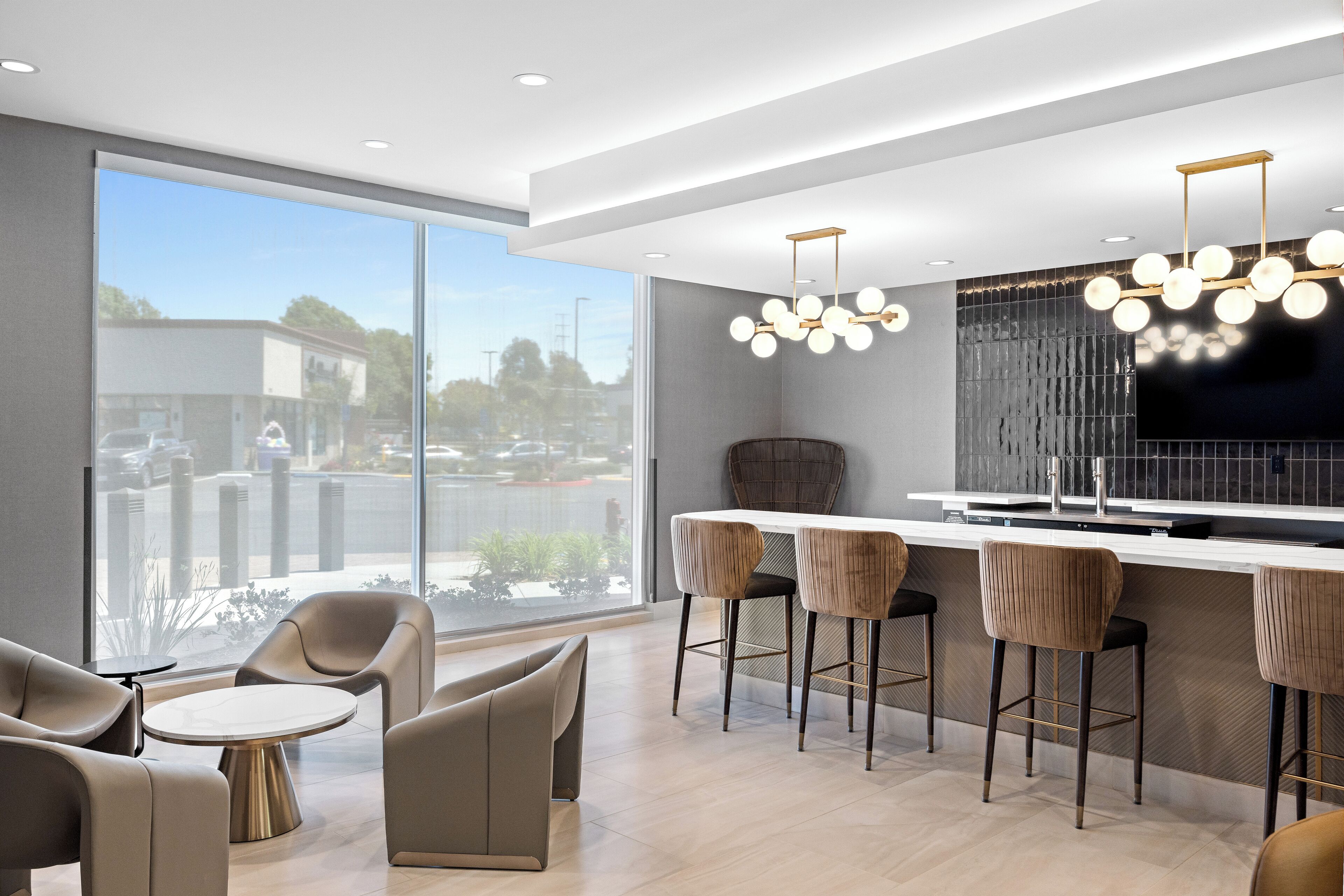A modern kitchen with a large window, bar stools, and a round table. - La Quinta Inn & Suites by Wyndham La Habra (La Habra)