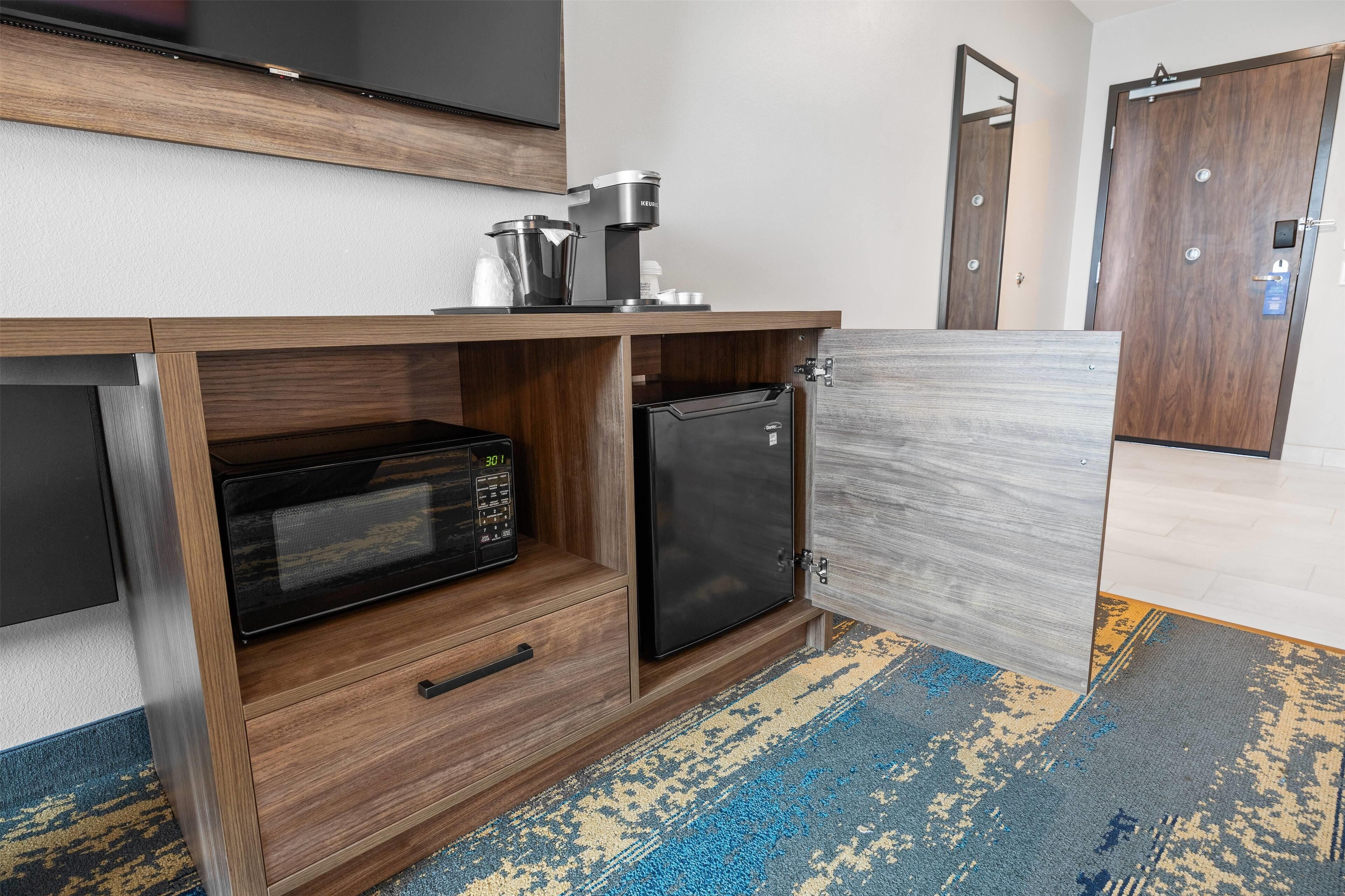 A kitchenette with a microwave, coffee maker, and refrigerator.
