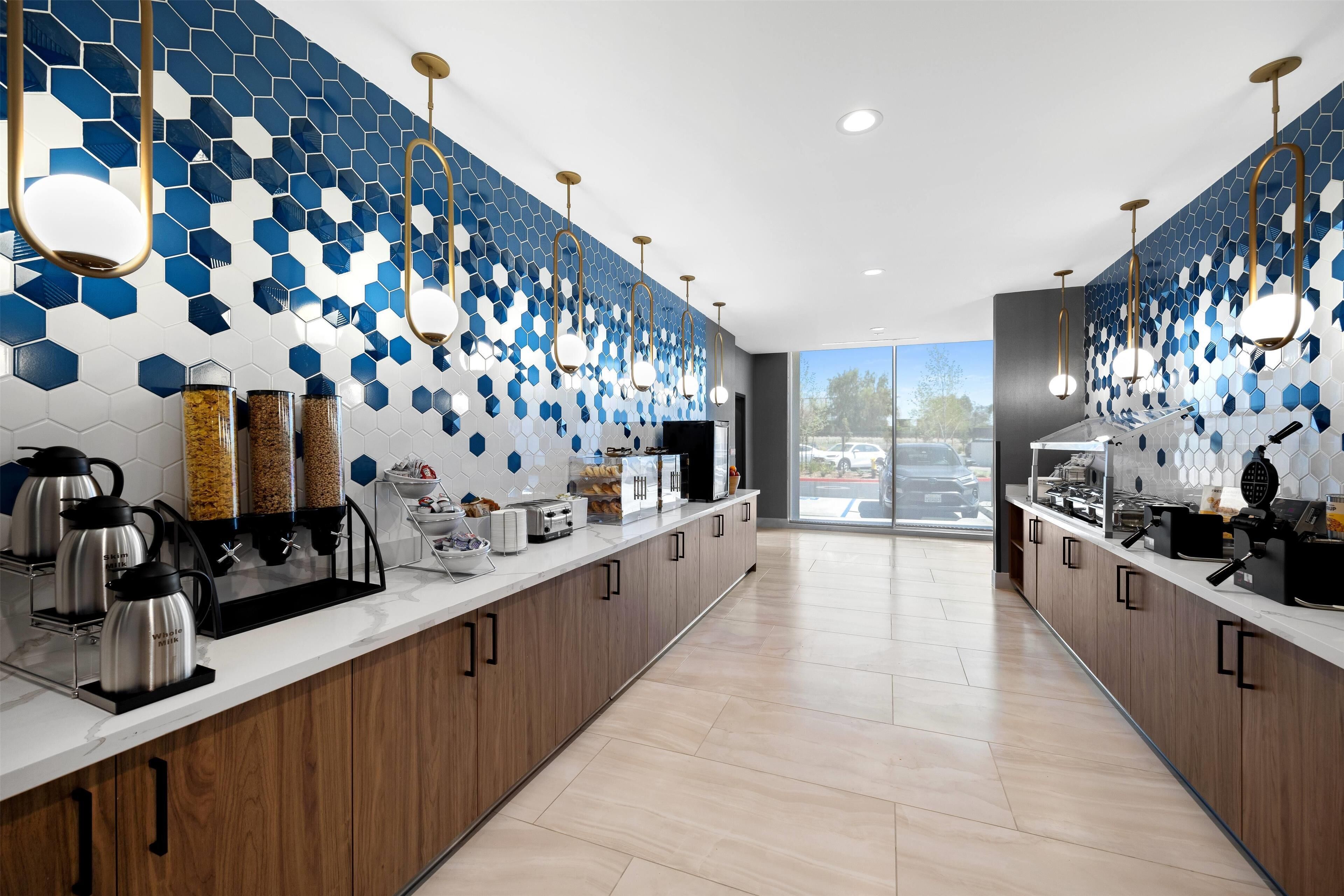 A modern kitchen with a long counter, hexagonal tile backsplash, and stainless steel appliances.