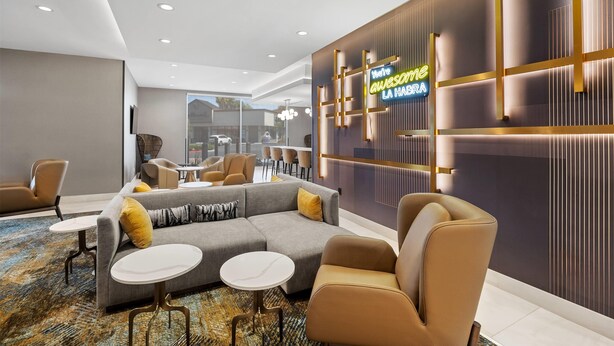 A modern hotel lobby with a sectional sofa, armchairs, and a patterned rug. - La Quinta Inn & Suites by Wyndham La Habra (La Habra)