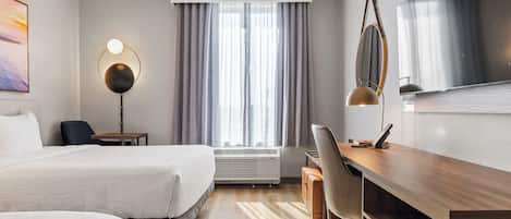 A hotel room with two beds, a desk, a chair, a TV, a lamp, and a window with curtains.