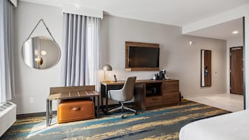 Habitación de hotel con cama, escritorio, silla y un espejo grande.