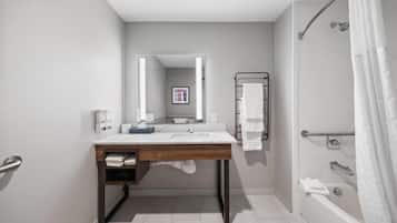 A modern bathroom with a wooden vanity, a large mirror, a shower with a glass door, and a towel rack.