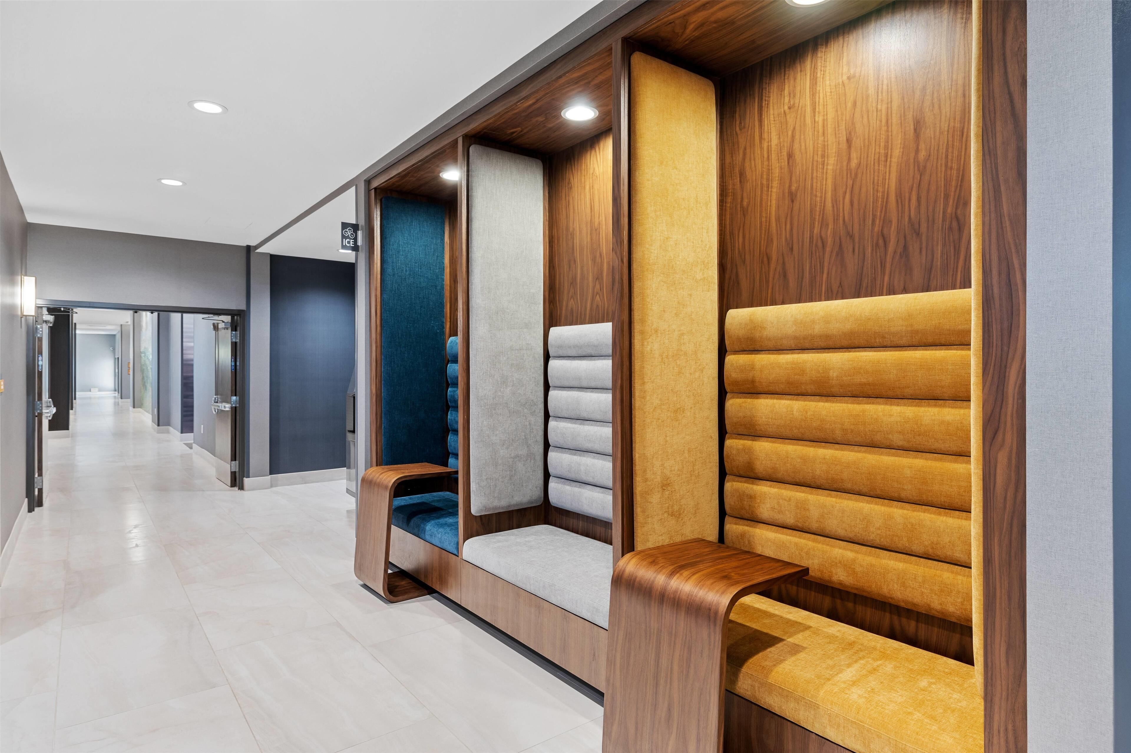 Un couloir d’hôtel moderne, agrémenté d’espaces de détente avec des panneaux de bois et des sièges rembourrés.
