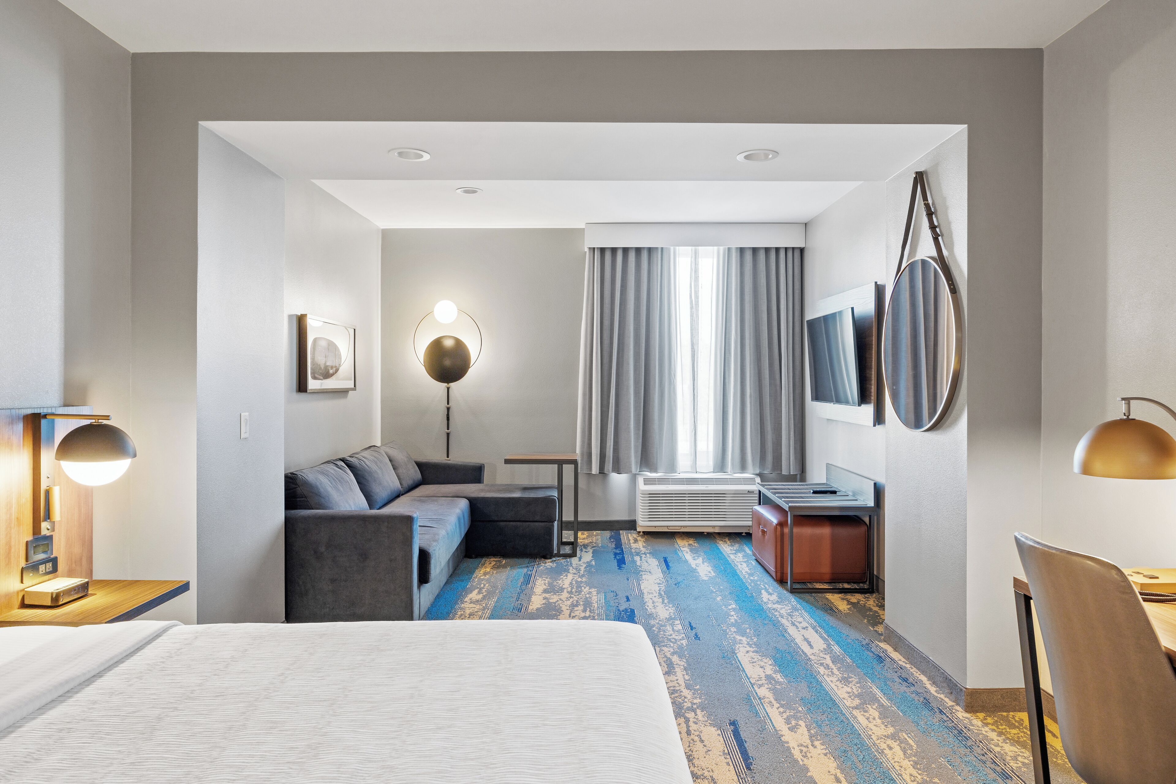 Ein modernes Hotelzimmer mit einem großen Bett, einer Couch, einem kleinen Tisch und einem Schreibtisch.