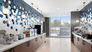 A modern kitchen with a breakfast bar, hexagonal tile backsplash, and pendant lighting. - La Quinta Inn & Suites by Wyndham La Habra (La Habra)