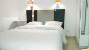 A hotel room with a large bed, two bedside tables, and two wall-mounted lamps. - T2 A/C côte d'Azur, piscine, plage á 350m, WIFI  (Vallauris)