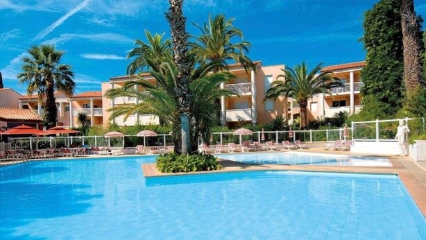A hotel pool area with multiple lounge chairs and umbrellas, surrounded by palm trees and a clear blue sky. - T2 A/C côte d'Azur, piscine, plage á 350m, WIFI  (Vallauris)