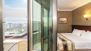A hotel room with a balcony, a bed, a chair, and a view of the city. - Crestium Taksim Prive&Spa (Istanbul)