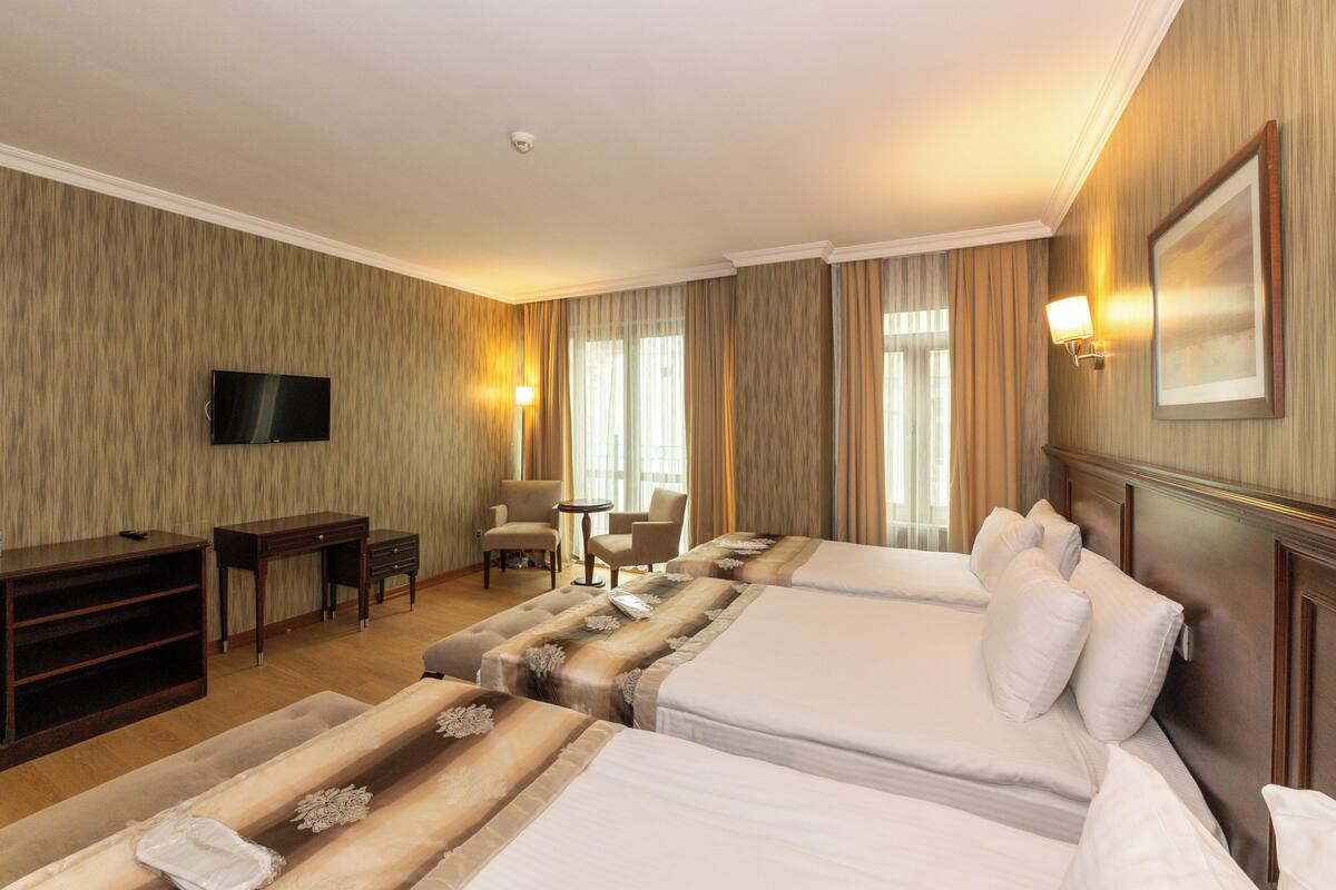 A hotel room with two beds, a TV, a desk, and a chair.