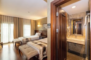 A hotel room with two beds, a sitting area, a bathroom with a sink and mirror, and a large window with curtains. - Crestium Taksim Prive&Spa (Istanbul)