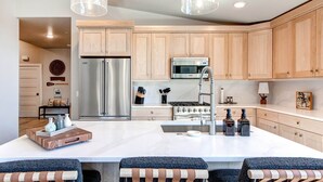 A modern kitchen with wooden cabinets, stainless steel appliances, and a central island with bar stools.