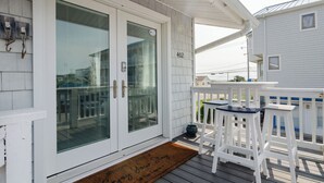 Une maison blanche avec le numéro 402 sur la porte, un porche avec un banc et un paillasson portant un message.