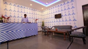 Ein Empfangsbereich mit Wand in blau-weißem Muster, einer Rezeption und einer Sitzecke mit gemusterten Stühlen.