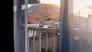 A view of a residential street with houses, a person pushing a stroller, and a mountain in the background. - Winter Whale Lodge (Kutchan)