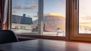 A room with a view of a mountain and buildings. - Winter Whale Lodge (Kutchan)