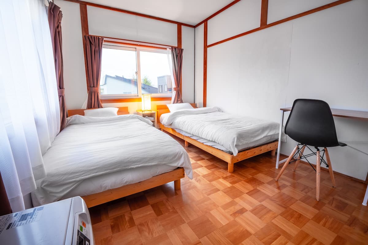 A hotel room with two beds, a desk, and a chair.