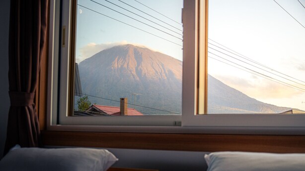 A room with a large window overlooking a mountain. - Winter Whale Lodge (Kutchan)