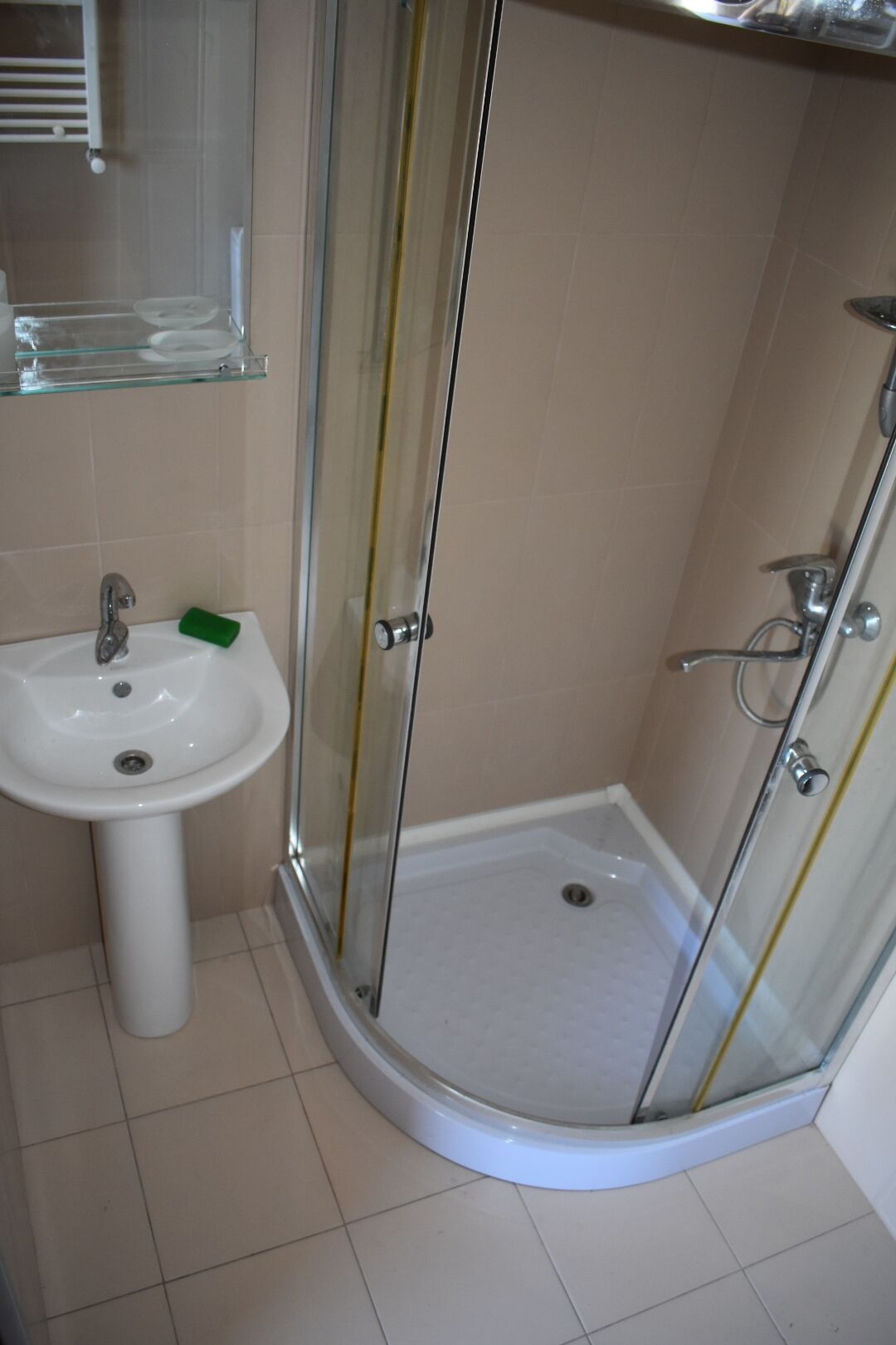 A bathroom with a glass-enclosed shower, a sink, and a mirror.