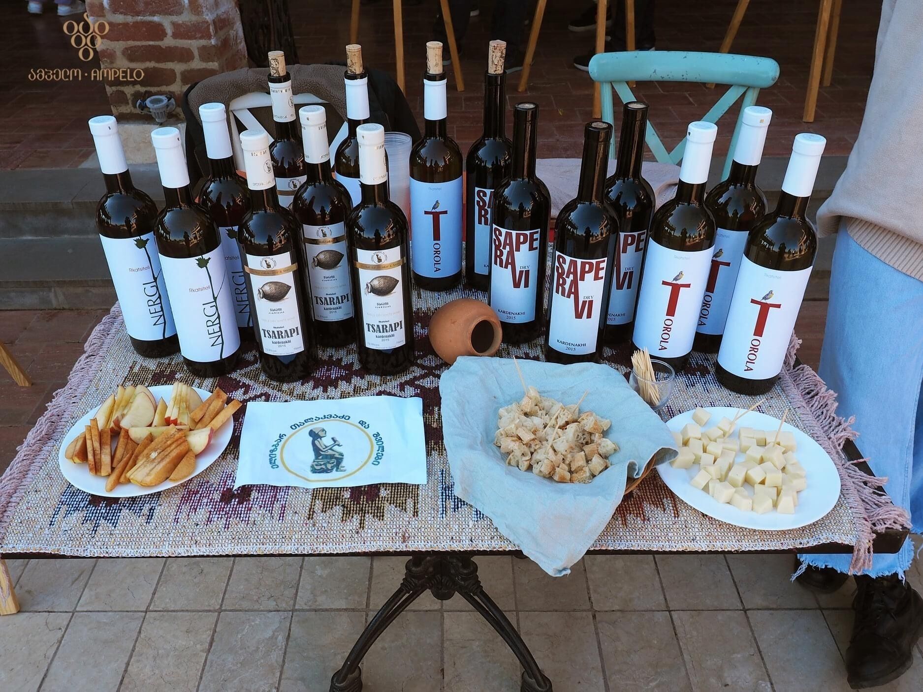 Una mesa con varias botellas de vino, platos de comida y un paño decorativo.