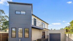 A modern two-story house with a flat roof, a garage, and a balcony. - Tranquility on Thompson (Cowes)