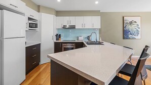 A modern kitchen with white cabinets, a stainless steel range hood, a microwave, and a built-in oven. - Tranquility on Thompson (Cowes)