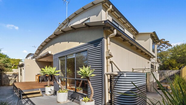 A modern house with a large glass window, a wooden deck, and potted plants. - Tranquility on Thompson (Cowes)