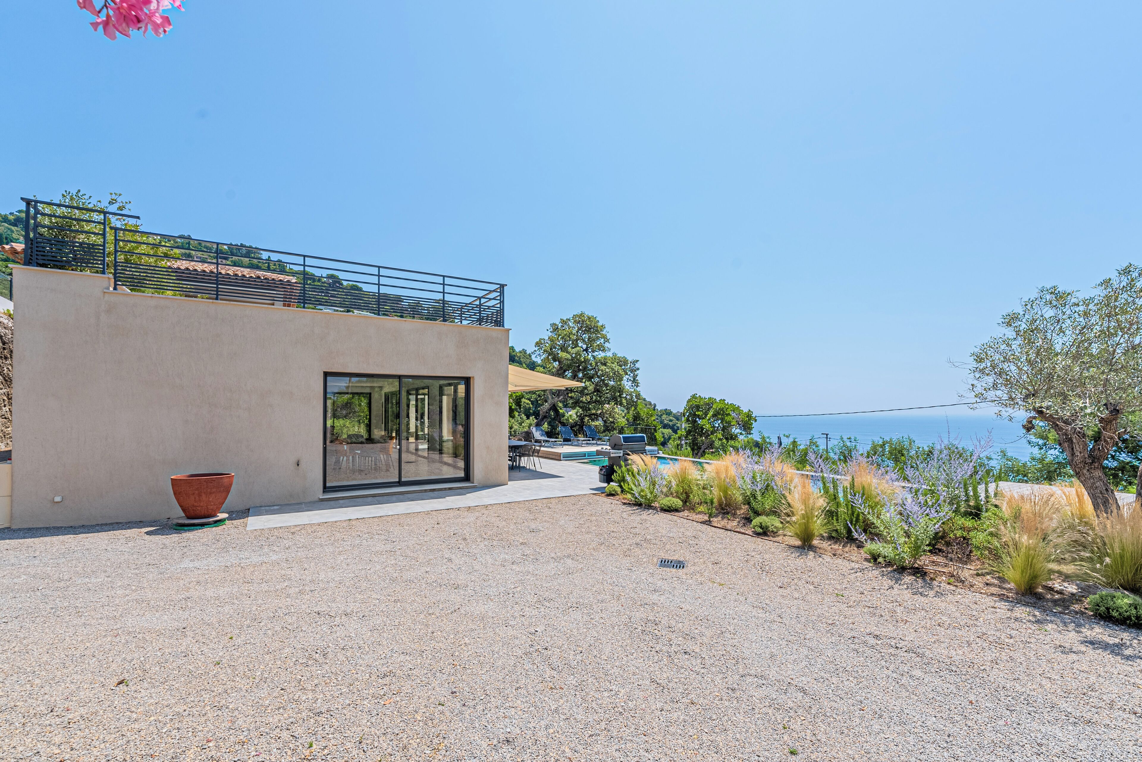 A modern building with a pool, outdoor seating, and a view of the sea.