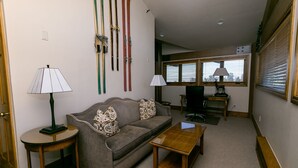 A living room with a sofa, two lamps, a coffee table, and skis on the wall. - Luxury Three Bedroom Suite with Three Kings 3 Suite (Park City)