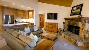 A modern living room with a stone fireplace, wooden cabinets, and a flat-screen TV. - Luxury Three Bedroom Suite with Three Kings 3 Suite (Park City)