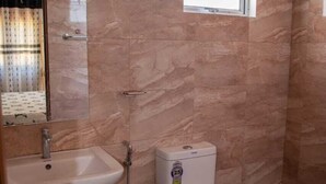 Ein Badezimmer mit Toilette, Waschbecken und einem Fenster.