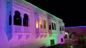 Un edificio con dettagli architettonici bianchi e decorativi e numerosi balconi, illuminato da luci LED colorate.